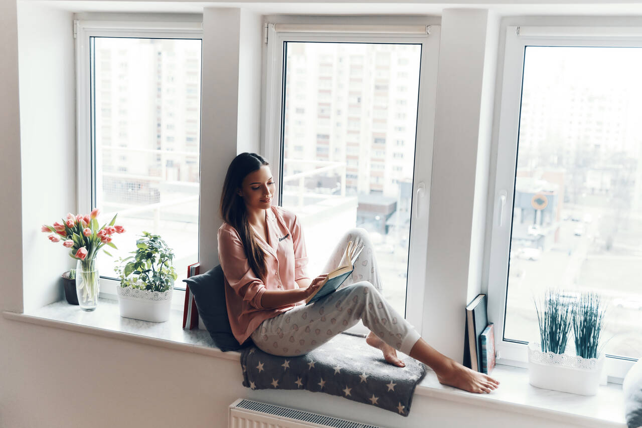 Person enjoying a peaceful moment by a window with natural light